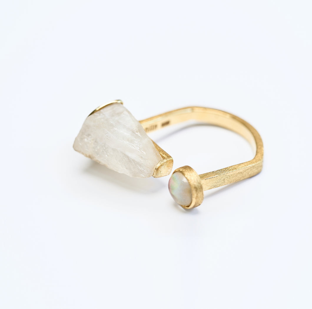 Gold ring with rock crystal and mother of pearl on a white background