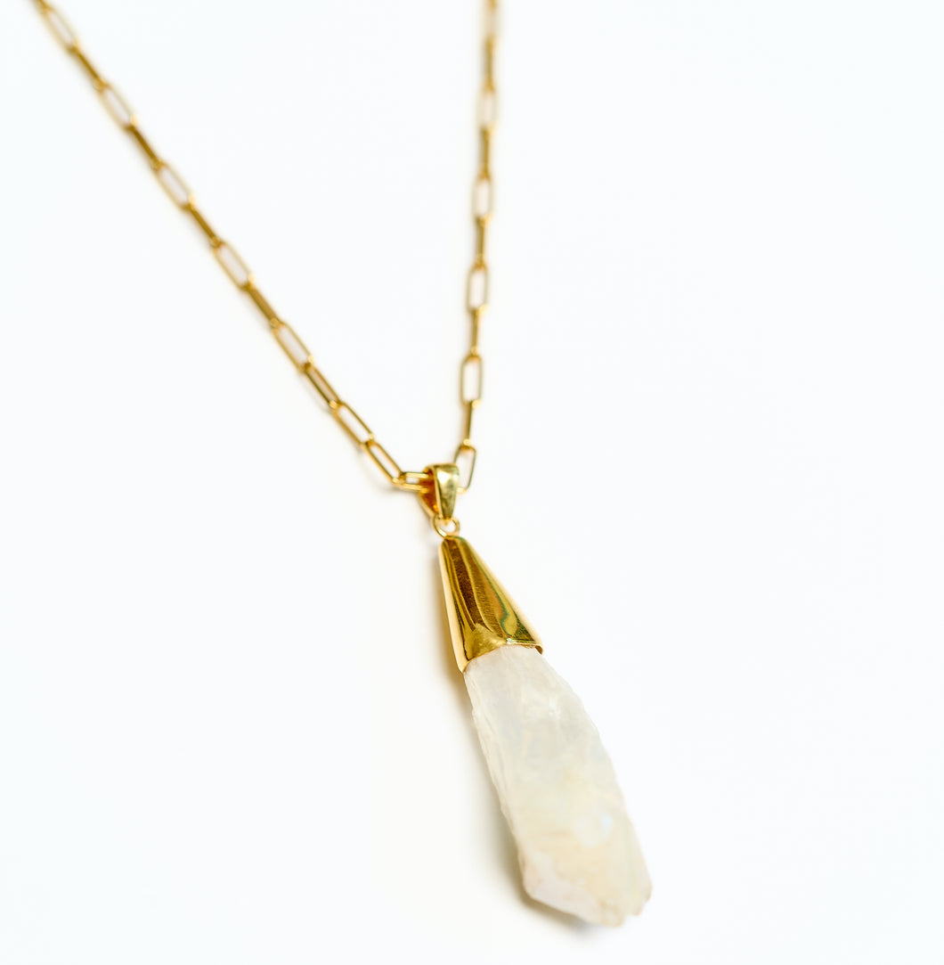Gold chain necklace with a raw rock crystal pendant on a white background
