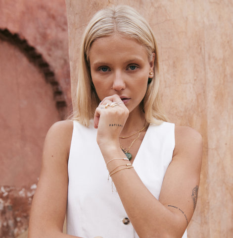 Gold bracelet with a mother of pearl bar charm on a white background